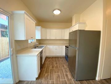 Merced house for rent - a kitchen with white cabinets and a stainless steel refrigerator