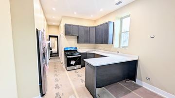 Chicago apartment for rent - a kitchen with black cabinets and a counter top and a stove