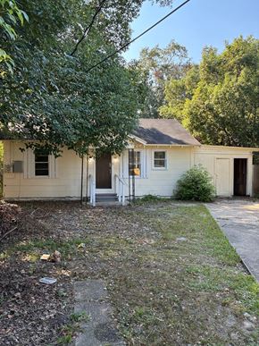 Mobile house for rent - A small white house with a brown roof and a tree in front.