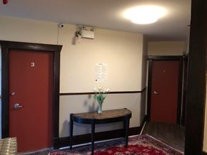 Vancouver apartment for rent - A room with a red door and a table with a vase of flowers on it.