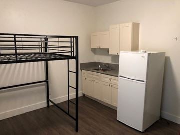 Vancouver apartment for rent - A white refrigerator sits in a kitchen next to a black bunk bed.