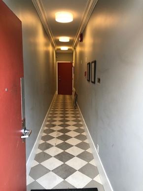 Vancouver apartment for rent - A long hallway with a checkered floor and a red door at the end.