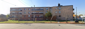 Toronto apartment for rent - A large brick apartment building with a parking lot in front.