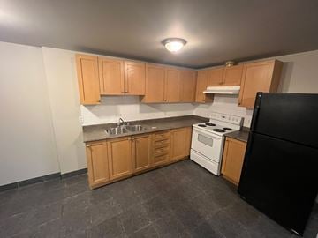 Brantford apartment for rent - A kitchen with wooden cabinets and black appliances.