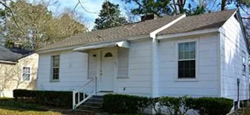 Mobile house for rent - A small white house with a porch and a front yard.