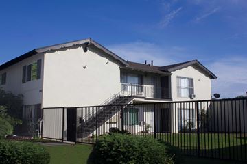 Anaheim apartment for rent - A white house with a black fence and a green lawn in front.
