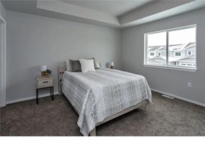 Waukee apartment for rent - A bedroom with a large bed and a window showing a view of houses.