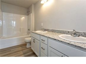Waukee apartment for rent - A white bathroom with a marble countertop and a white toilet.