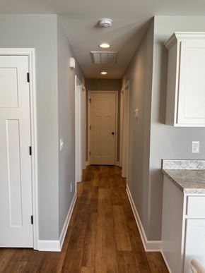 Hopkinsville house for rent - a hallway with wood floors and white cabinets and a white door