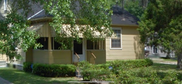 Mobile house for rent - A yellow house with a porch and a tree in front.