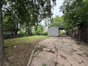 Tulsa house for rent - A cracked concrete pathway leads to a small building in a backyard.
