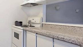 Toronto apartment for rent - a kitchen with white cabinets and a counter top and a stove