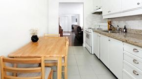 Toronto apartment for rent - a kitchen with a wooden table and white cabinets