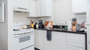 Toronto apartment for rent - a white kitchen with white appliances and black counter tops