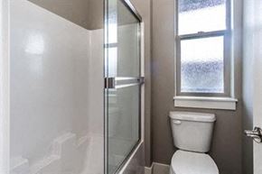 Bend apartment for rent - A white toilet sits next to a glass shower stall in a bathroom.