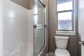 Bend apartment for rent - A white toilet sits next to a glass shower stall in a bathroom.
