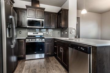 Bend apartment for rent - A modern kitchen with dark wood cabinets and stainless steel appliances.