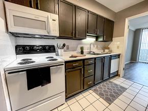 St. Louis apartment for rent - A kitchen with white appliances and black cabinets.