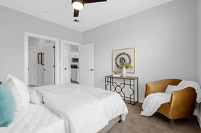 St. Louis apartment for rent - A bedroom with a white bed and a brown chair.