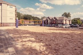 Clemson apartment for rent - a sandy area in front of a building with a volleyball court
