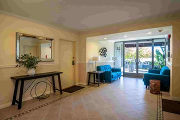 Santa Monica apartment for rent - A living room with a mirror, a blue sofa, and a table with a vase of flowers.