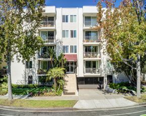 Santa Monica apartment for rent - A white apartment building with a red awning and trees in front.