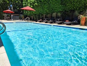Van Nuys apartment for rent - A swimming pool with red umbrellas and lounge chairs.