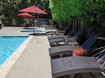 Van Nuys apartment for rent - A poolside area with lounge chairs and umbrellas.