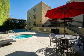 Van Nuys apartment for rent - A red umbrella is on a table outside a building.