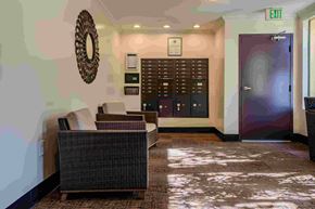 Van Nuys apartment for rent - A room with a couch, a mirror, and a wall with a clock.
