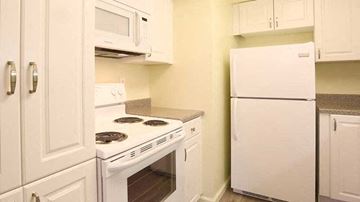 Bryn Mawr apartment for rent - A white kitchen with a stove, microwave, and refrigerator.