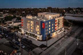 Los Angeles apartment for rent - A modern multi-story building with blue and red accents is lit up at dusk.