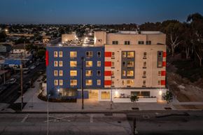 Los Angeles apartment for rent - A modern building with a combination of blue, red, and beige colors is illuminated at night.