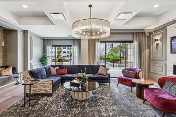 Hauppauge apartment for rent - A large, modern living room with a dark rug and a large chandelier.
