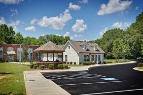 York apartment for rent - A small white building with a porch is surrounded by a parking lot.