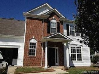 Charlotte house for rent - a red brick house with white siding and a garage