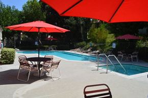 Glendora apartment for rent - a swimming pool with tables and chairs under a red umbrella