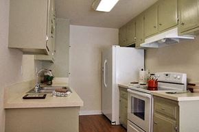 Orange apartment for rent - a kitchen with a stove refrigerator and a sink