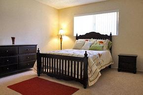 Orange apartment for rent - a bedroom with a bed and a dresser and a window