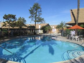 Orange apartment for rent - a large swimming pool with tables and chairs around it