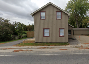 Mono apartment for rent - A two-story house with a brown siding and red window frames.