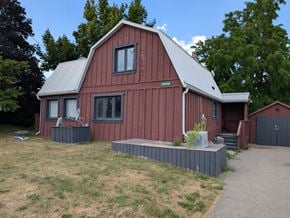 Mulmur house for rent - A red barn with a metal roof and a grey concrete walkway in front.