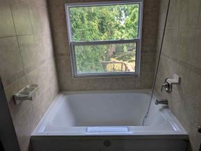 Mulmur house for rent - A bathroom with a tub and a window overlooking a backyard.