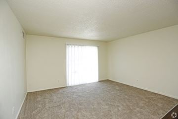 Kansas City apartment for rent - a spacious living room with carpet and a window