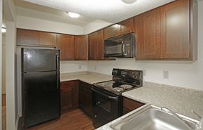 Kansas City apartment for rent - a kitchen with black appliances and granite counter tops and wooden cabinets