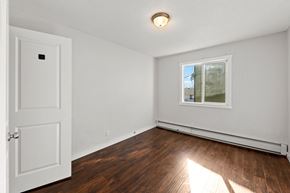 Calgary apartment for rent - A room with a white door and a window with a view of trees outside.