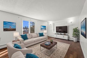 Calgary apartment for rent - A living room with a white couch, a coffee table, and a large window.