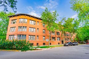 Chicago apartment for rent - a large brick building with cars parked in front of it