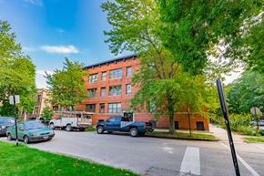 Chicago apartment for rent - a large red brick building on a street corner with trucks parked in front of it