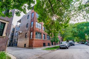 Chicago apartment for rent - a red brick building on a city street with cars parked